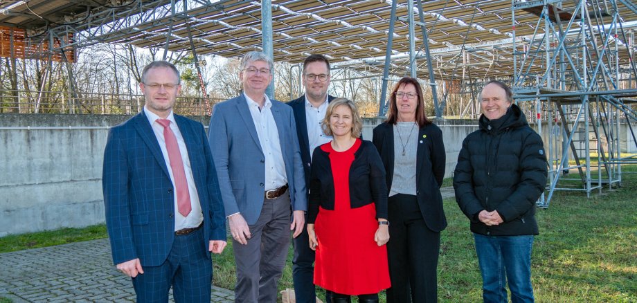 Die faltbare Solaranlage über dem Klärwerk Neuwied bei Inbetriebnahme mit einer Personengruppe davor.