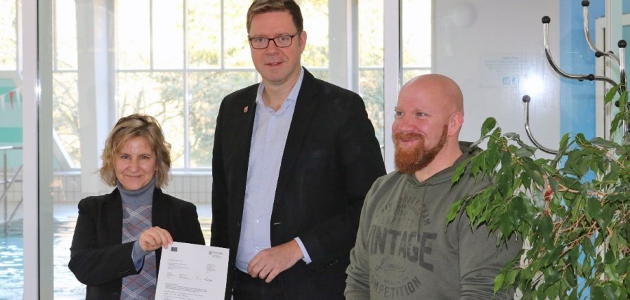 Klimaschutz- und Energieministerin Katrin Eder (links) überreicht EFRE-Förderbescheid in Höhe von rund 873.000 Euro an Bürgermeister Marcus Heintel (Mitte) und den Bäderbetriebsleiter Daniel Schön (rechts).